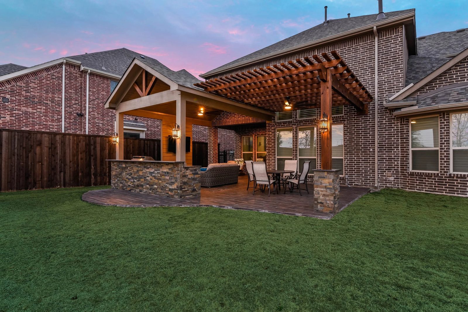 Outdoor kitchen and dining patio illuminated with warm string lighting at night